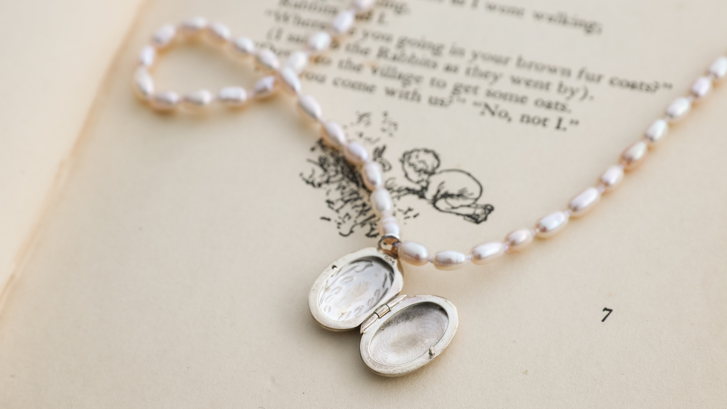 pearl necklace with silver locket on book